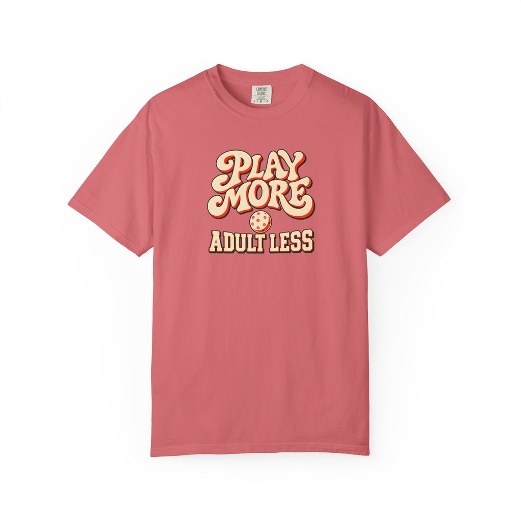 Watermelon colored Play More Adult Less pickleball t-shirt with playful cream script typography.