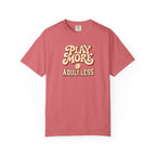 Watermelon colored Play More Adult Less pickleball t-shirt with playful cream script typography.