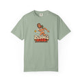 Sage colored Paddle Kiss pickleball t-shirt with playful vintage paddle-and-pickleball character graphic.