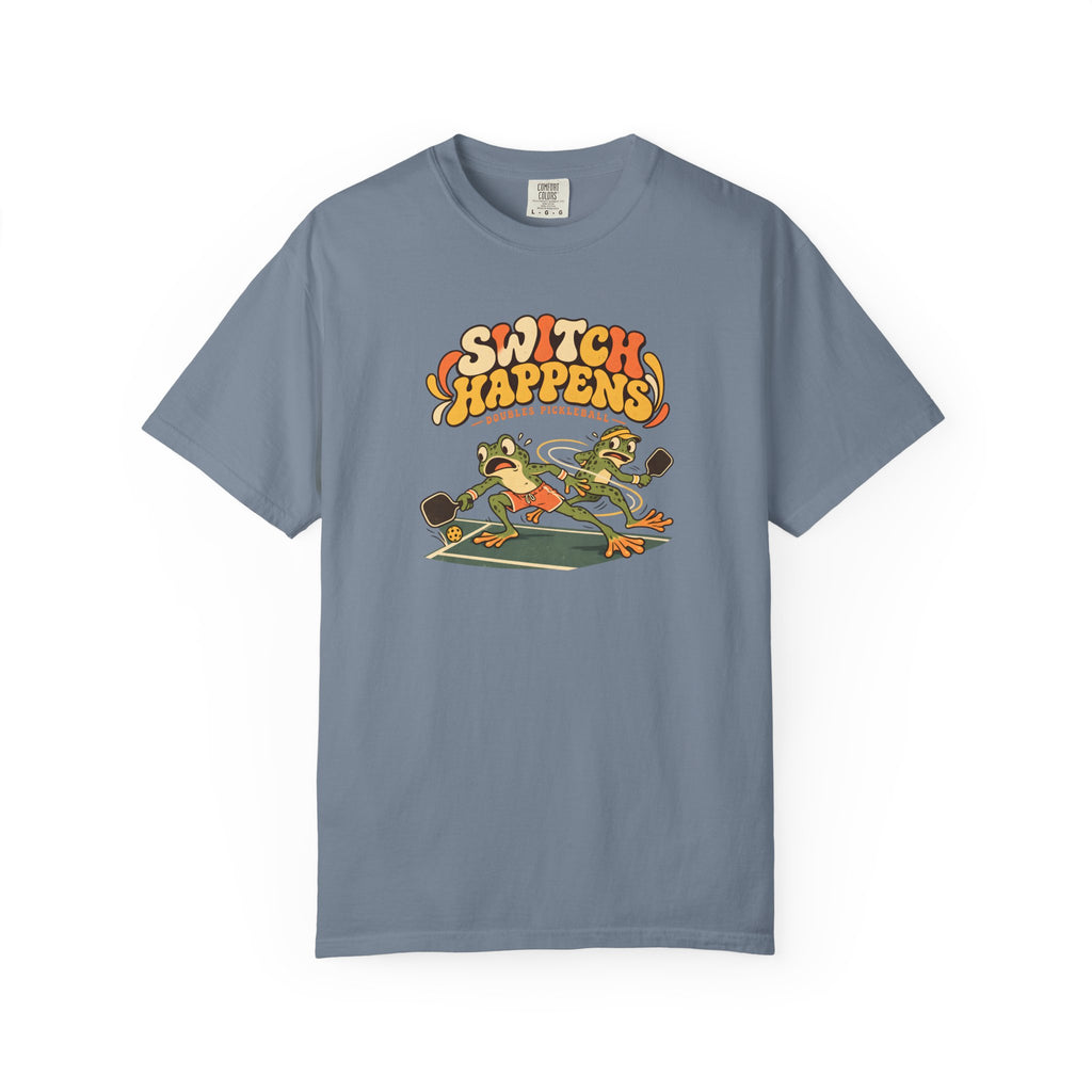 Blue-gray colored Switch Happens pickleball t-shirt with colorful retro court graphic and bold curved lettering.